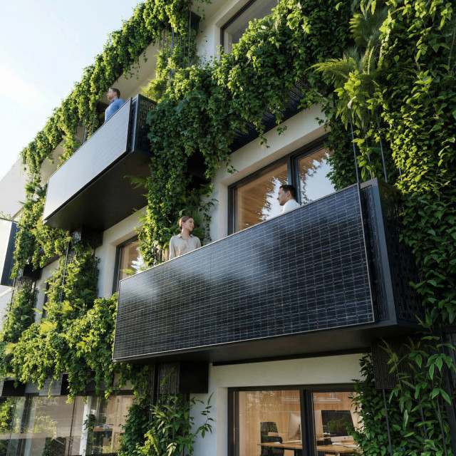 Modernes BÃ¼rogebÃ¤ude mit begrÃ¼nter Fassade, Balkonen und groÃen Fenstern, die den Blick auf einzelne BÃ¼roflÃ¤chen freigeben.